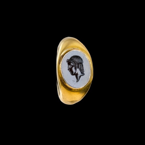 A Roman gold ring set with a garnet intaglio. Head of Apollo.